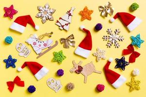 Top view of Christmas decorations and Santa hats on yellow background. Happy holiday concept photo