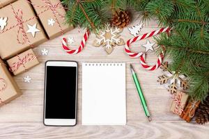 Christmas background with gift boxes, mobile phone with back screen and blank notebook, copy space. Template for new year goal or resolutions. Christmas mockup. Flat lay, top view photo