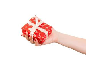 Woman hands give wrapped Christmas or other holiday handmade present in red paper with Gold ribbon. Isolated on white background, top view. thanksgiving Gift box concept photo