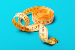 Close up of tangled measuring tape on blue background. Fitness and healthy diet concep with perspective view photo