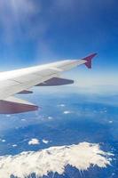 vista desde la ventana del avión que vuela sobre las montañas foto