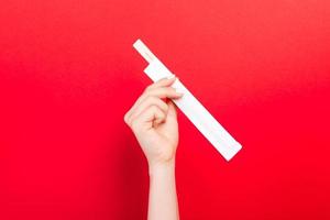 Woman's hand holding chopsticks in a pack on red background. Chinese food concept with empty space for your design photo