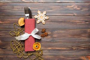 Top view of utensils on festive napkin on wooden background. Christmas decorations with dried fruits and cinnamon. New year dinner concept with copy space photo