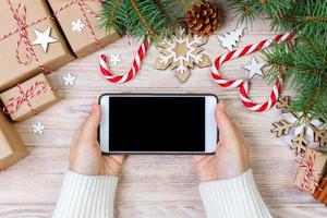 mujer que usa un teléfono inteligente con pantalla en blanco, marco festivo trumpery. búsqueda de regalos de navidad, compras en línea, descuentos de temporada y concepto de venta