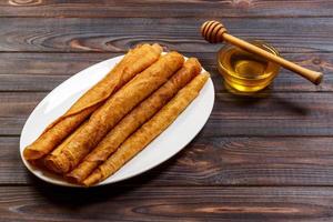 Stack of tasty pancakes with honey in jar on wooden bachground photo