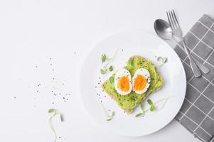 pan con aguacate, verduras, frutas y huevo sobre fondo blanco, concepto de desayuno saludable foto