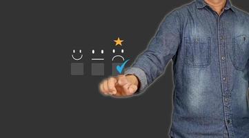 Customer Service and Satisfaction Concept Businessman touching virtual screen on unhappy face icon to express dissatisfaction with service Very bad rating. Gray background with empty space. photo