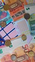 Stack of French grid of loto and gambling games with euro banknotes and coins on them video