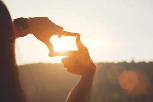 Planning and vision concept of new year's start, woman hands making frame gesture find focus at sunset, woman looking for perspective to capture the meaning of a clear upcoming target. photo