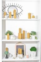 white simple shelves with hand made beeswax candles ans concrete decorative home accessories. potted plants in loft style cement pots. modern trendy simple house decor. photo