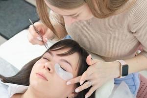 woman cosmetologist applying under eye patch to isolate eyelashes during lash extension procedure. photo