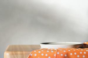 Empty concrete plate on orange tablecloth on wooden table over grunge grey background. side view. copy space for food placement photo