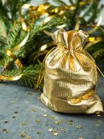 Fir branches on the grey concrete background with gold stars. New Year Christmas. Golden bag with gifts photo