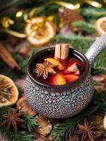 vino caliente de Navidad con canela, naranja y anís estrellado en un cuenco de cerámica con decoraciones de invierno foto