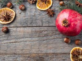 Pomegranate spruce branches star anise nuts, cinnamon and winter spices on wooden background, Rustic style Copy space photo