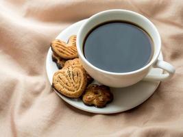 Cup of coffee with homemade cookies on the bed blankets photo