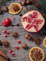 Pomegranate spruce branches star anise nuts, cinnamon and winter spices on wooden background, Rustic style photo