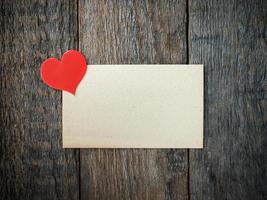 Paper heart on an old sheet of paper on rustic wooden background photo