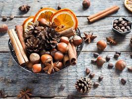 Winter ingredients nuts, cones, oranges, cinnamon star anise in a bowl. Rustic style photo