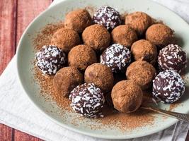 Homemade chocolate truffles with cocoa and coconut on the plate photo