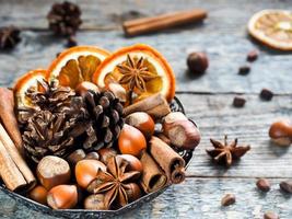 ingredientes de invierno nueces, conos, naranjas, canela anís estrellado en un bol. estilo rústico foto