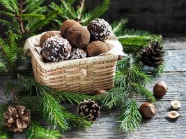 Christmas chocolate truffles in a wicker box the fir tree branches on wooden table photo