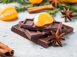Fresh tangerines with branches of Christmas tree, star anise chocolate cinnamon on gray concrete background photo