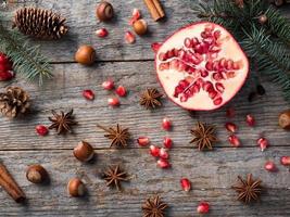 Pomegranate spruce branches star anise nuts, cinnamon and winter spices on wooden background, Rustic style photo