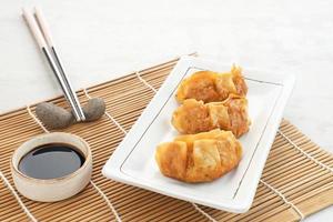 Gyoza, deep fried dumpling with juicy chicken and cabbage. Served in white plate with soy sauce photo