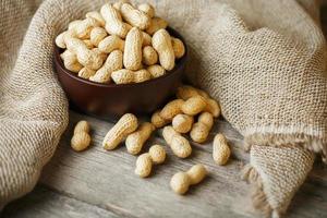 Peanuts in the shell, in a wooden cup on the table. photo