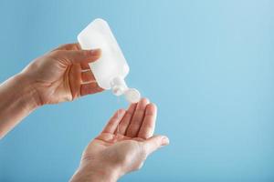 A bottle of Disinfectant gel in your hands on a blue background. Antiseptic treatment of hands from bacteria Sanitizer. photo