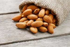 nueces de almendras en una bolsa de arpillera sobre un fondo gris de madera. foto