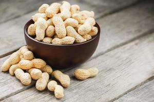 Peanuts in the shell, in a wooden cup on the table. photo