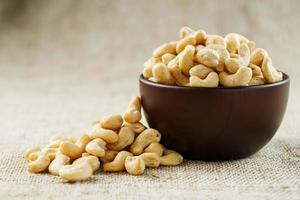 Cashew nuts in a wooden bowl on a burlap cloth background. photo