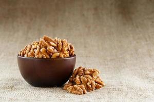 Peeled walnuts in a wooden, dark brown cup on a burlap cloth. photo