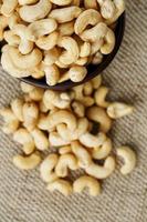 Cashew nuts in a wooden bowl on a burlap cloth background. photo