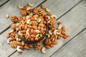 Wooden bowl with mixed nuts on a wooden gray background. Walnut, pistachios, almonds, hazelnuts and cashews, walnut. photo