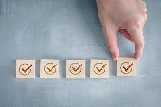 Checklist, Task list, Survey and assessment. Quality Control. Goals achievement and business success. Man's hand add check mark on wooden block for complete check list. photo