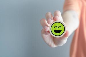 Feedback rating and service review. Customer experience, Mental health assessment, World mental health day, Think positive, Emotion, Satisfaction. Hand showing green happy smile face. photo