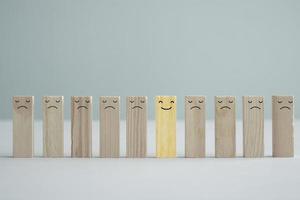 Happy smiling face among unhappy faces on wooden blocks. Positive thinking, Unique, Individuality, Difference, Emotion, Positive thinking, Mental health assessment, World mental health day concept. photo