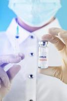 Ampoule with the vaccine against the Virus from diseases on a blue background in the hands of a doctor, scientist in gloves and a mask. Free space on the ampoule label for text. photo