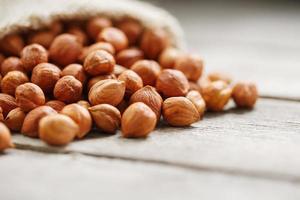 Chiselled hazelnuts in a bag of burlap on a gray wooden table. Organic Fresh Harvested photo