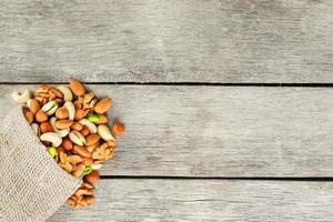 Mix of different nuts in a wooden cup against the background of fabric from burlap. Nuts as structure and background, macro. Top view. photo