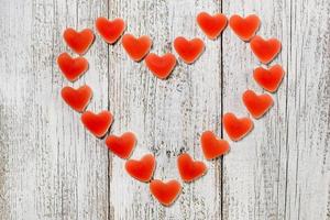 Red hearts candy forming big heart on white wooden background. Concept for Valentines day photo