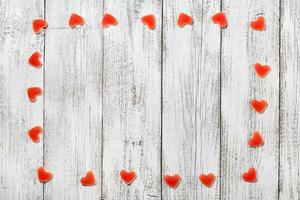 Frame made of red heart shaped candies on white wooden background for valentine day photo