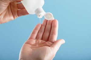 A bottle of Disinfectant gel in your hands on a blue background. Antiseptic treatment of hands from bacteria Sanitizer. photo