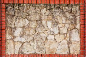 Wall of natural light stone in a red brick frame. photo