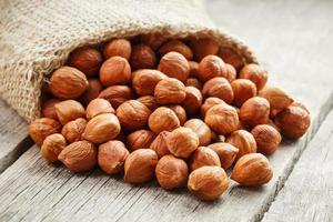 Chiselled hazelnuts in a bag of burlap on a gray wooden table. Organic Fresh Harvested photo