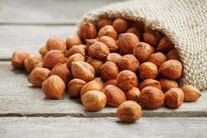 Chiselled hazelnuts in a bag of burlap on a gray wooden table. Organic Fresh Harvested photo