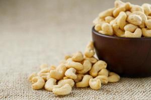 Cashew nuts in a wooden bowl on a burlap cloth background. photo